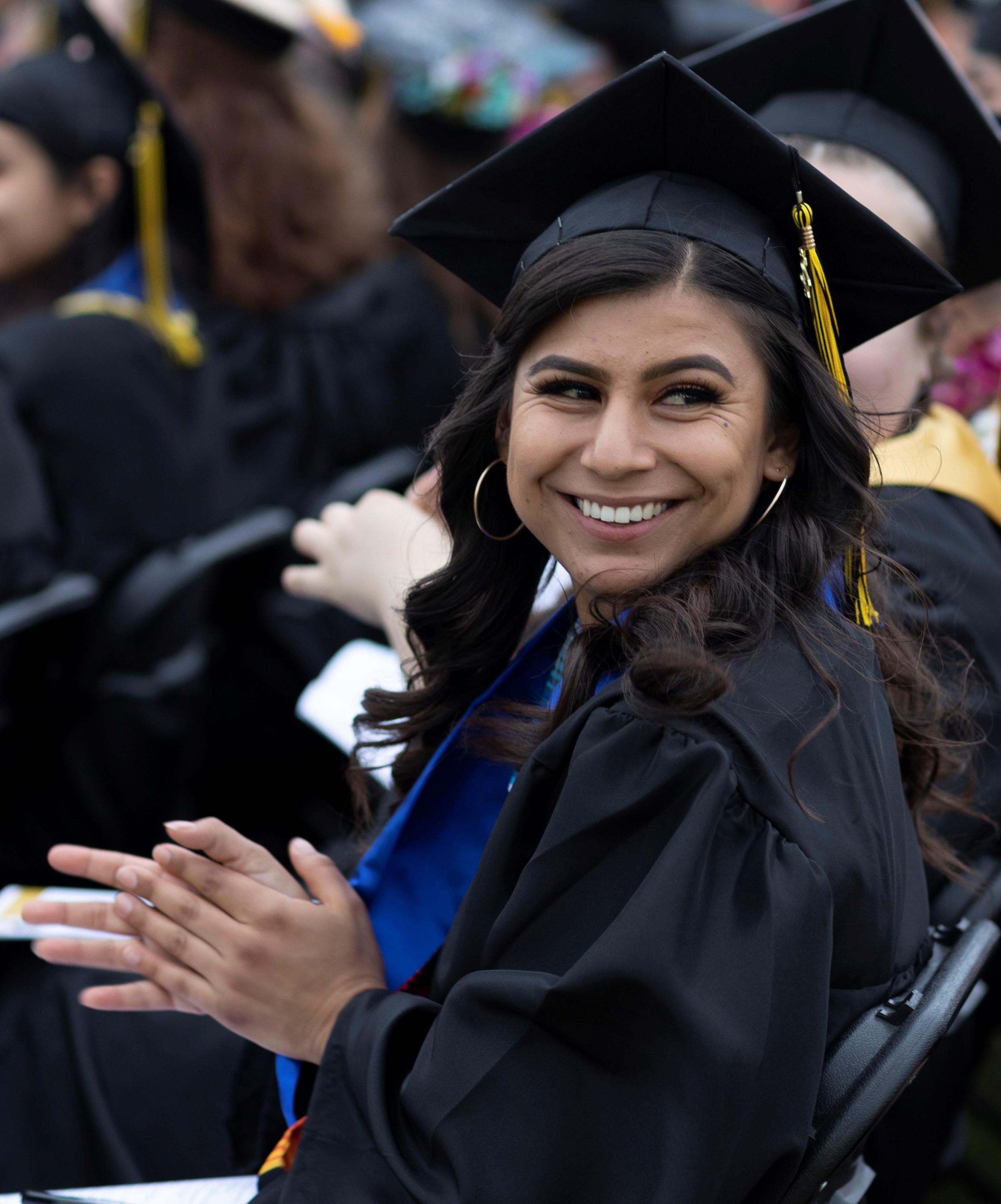 Student sitting at graduation smiling